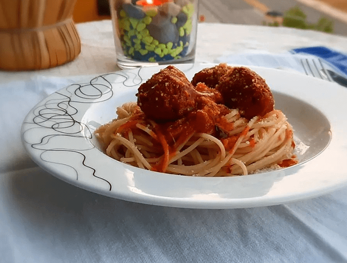 Prato branco com duas almôndegas green cuisine à moda do henrique e um garfo do lado direito